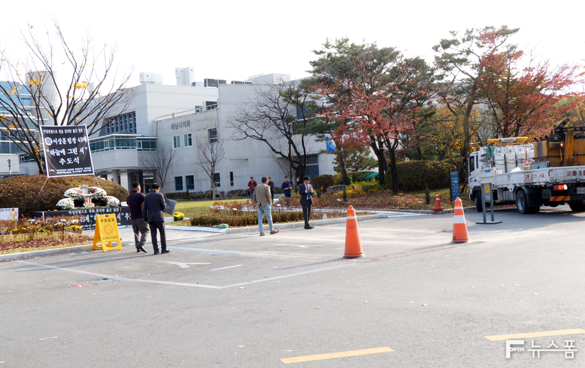 하남시 공무원 (故) 이상훈 팀장에 대한 49재 추도식 현장. 화분들이 안쪽으로 모두 옮겨져 있고 주차선을 지운 흔적이 남아 있다. 공사차량의 모습도 보인다.